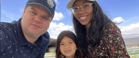 A family photo of Travis with his wife and daughter.